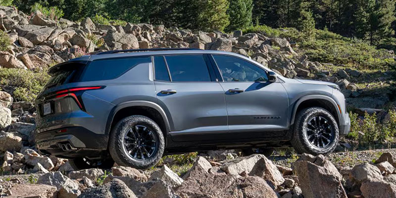 Gray Chevrolet SUV navigating rocky terrain, shown from a side angle with rugged off-road tires and tinted windows