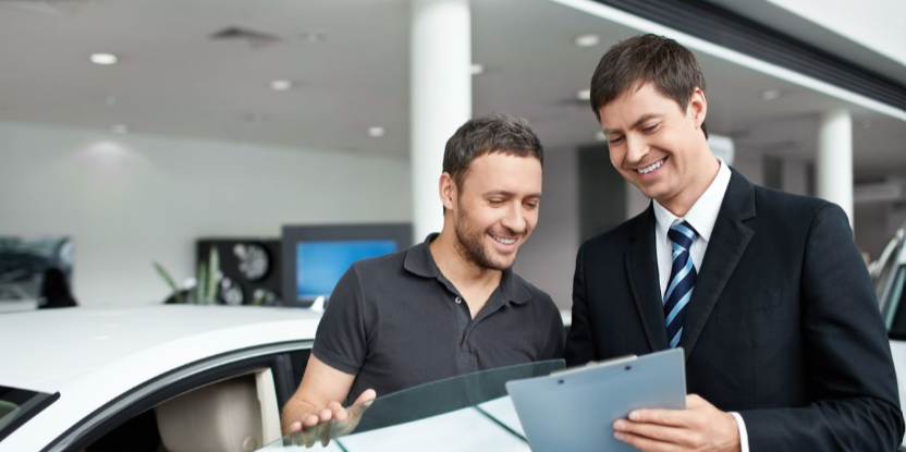 Customer reviewing vehicle details with dealership representative in a showroom.